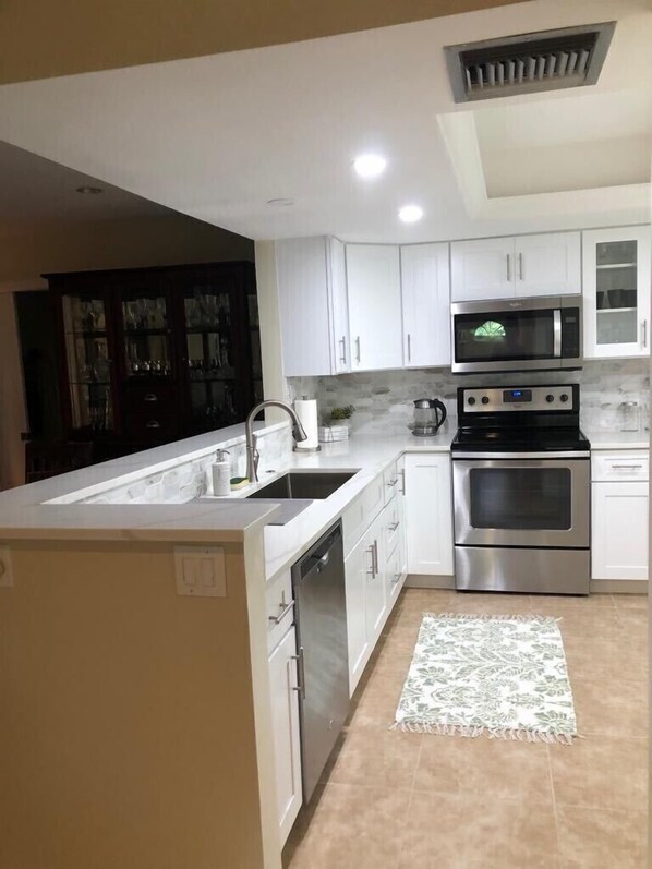 Una cocina moderna con armarios blancos, microondas integrado, horno doble y una isla grande con fregadero.