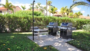 An outdoor patio with two barbecue grills, a table, and chairs. -   Outstanding Location in Maui  South Kihei & Wailea  (Kihei)