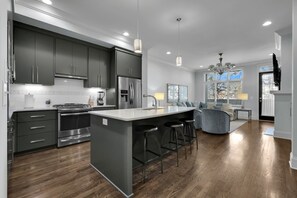 A modern kitchen with dark cabinets, stainless steel appliances, and a central island with bar stools.