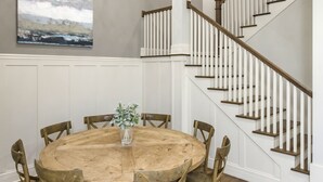 A dining area with a round wooden table and chairs, a chandelier, and a staircase with white railings. - FREE NIGHT DEAL! DOWNTOWN 1MI TO BROADWAY! #3 of 6 HOMES! Rooftop Deck BY VANDY! (Nashville)