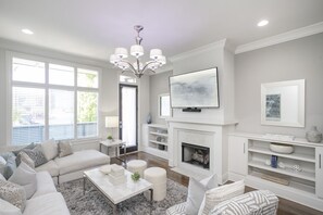 Un salon moderne avec une cheminée, un grand téléviseur et un coin salon confortable.
