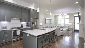 A modern kitchen with grey cabinets, stainless steel appliances, and a central island with bar stools. - FREE NIGHT DEAL! DOWNTOWN 1MI TO BROADWAY! #3 of 6 HOMES! Rooftop Deck BY VANDY! (Nashville)
