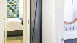 A hallway with a wooden floor, a sliding door, and a bathroom with a mirror and sink. - Upgraded Suite-Temple Square, Downtown Salt Lake City, Convention Center (Salt Lake City)