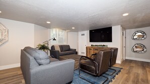 A modern living room with a grey sofa, a brown leather chair, a coffee table, and a TV mounted on the wall. - Upgraded Suite-Temple Square, Downtown Salt Lake City, Convention Center (Salt Lake City)