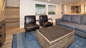 A modern living room with a staircase, two leather chairs, a grey sofa, and a patterned rug. - Upgraded Suite-Temple Square, Downtown Salt Lake City, Convention Center (Salt Lake City)