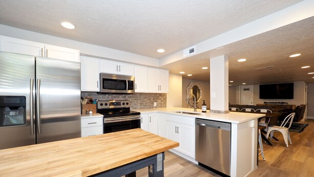 A modern kitchen with stainless steel appliances, white cabinetry, and a wooden island. - Upgraded Suite-Temple Square, Downtown Salt Lake City, Convention Center (Salt Lake City)