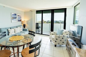 Uma sala de estar moderna com uma mesa de jantar de vidro, dois sofás e uma varanda com vista para a cidade.