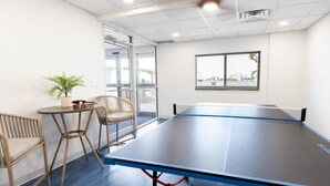 Una mesa de ping pong en una habitación con vista a un paisaje urbano a través de una ventana.