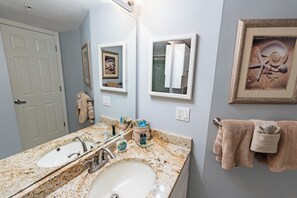 A bathroom with two sinks, a mirror, and a framed picture on the wall.