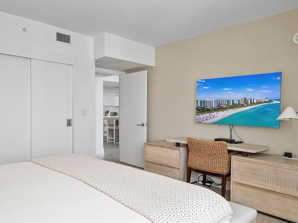 A hotel room with a bed, a desk with a chair, a large window with a beach view, and a wardrobe. - Luxurious 1/1 Ocean View Condo 1009 - Located at 1 Hotel & Homes South Beach (Miami Beach)