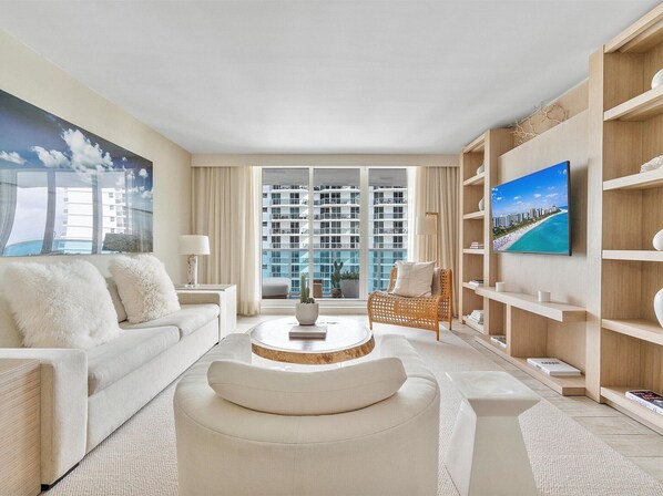 Relax in a stylish living room with a large flat-screen TV, comfortable sofa, and wicker armchair.