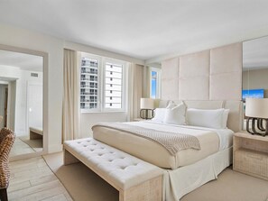 Relax in a spacious room with a large bed, tufted headboard, and matching bench, plus two bedside tables and a large mirror.