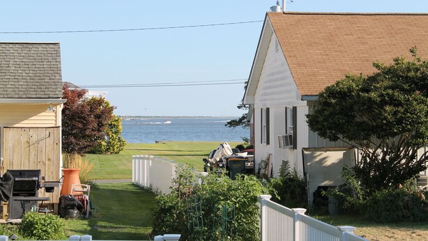 A residential area with a view of the water, houses, and a grassy lawn. - WALK to Beach, Town of Dewey w/LARGE Heated POOL thru Oct, HOT TUB and fire pit! (Dewey Beach)