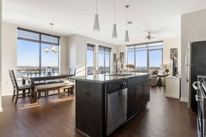 Uma cozinha moderna com ilha central, amplas janelas e um espaço de jantar com bancos.