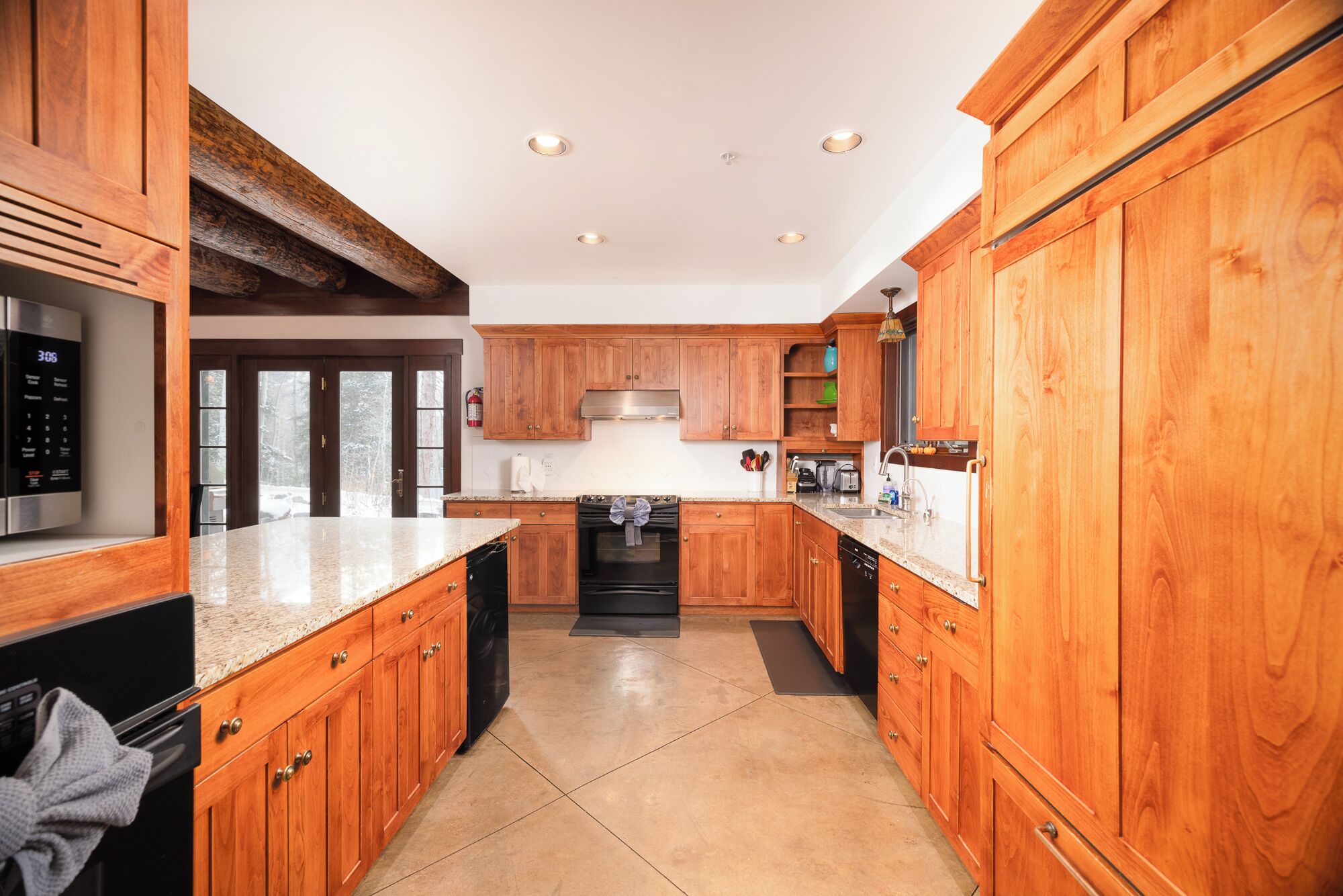 A modern kitchen with wooden cabinets, stainless steel appliances, and a granite countertop.