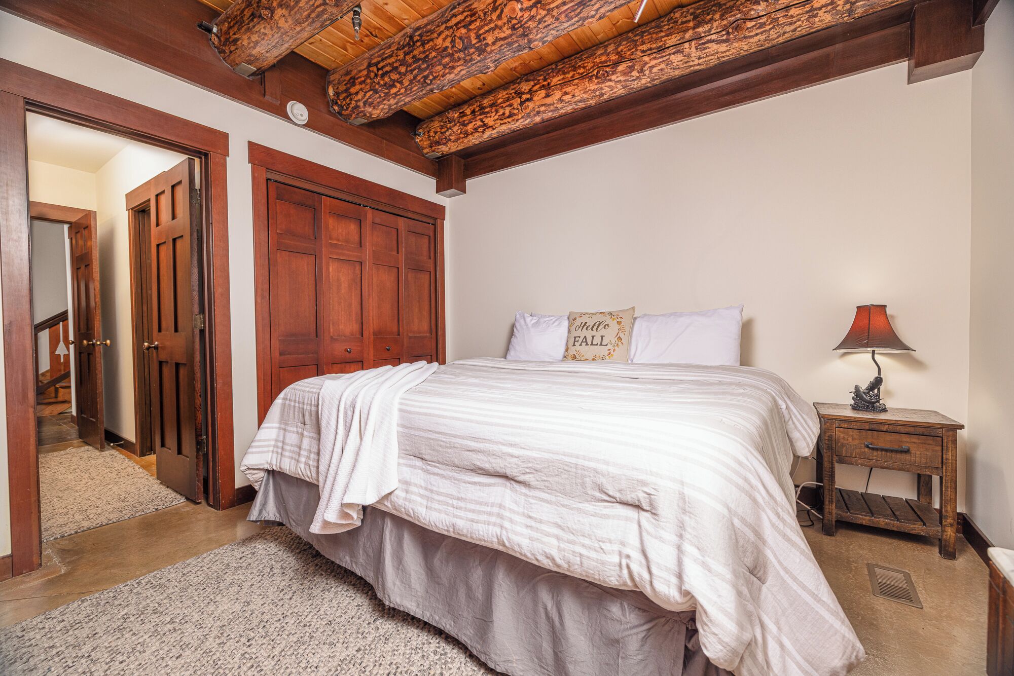 A bedroom with a large bed, wooden wardrobe, and a nightstand with a lamp.