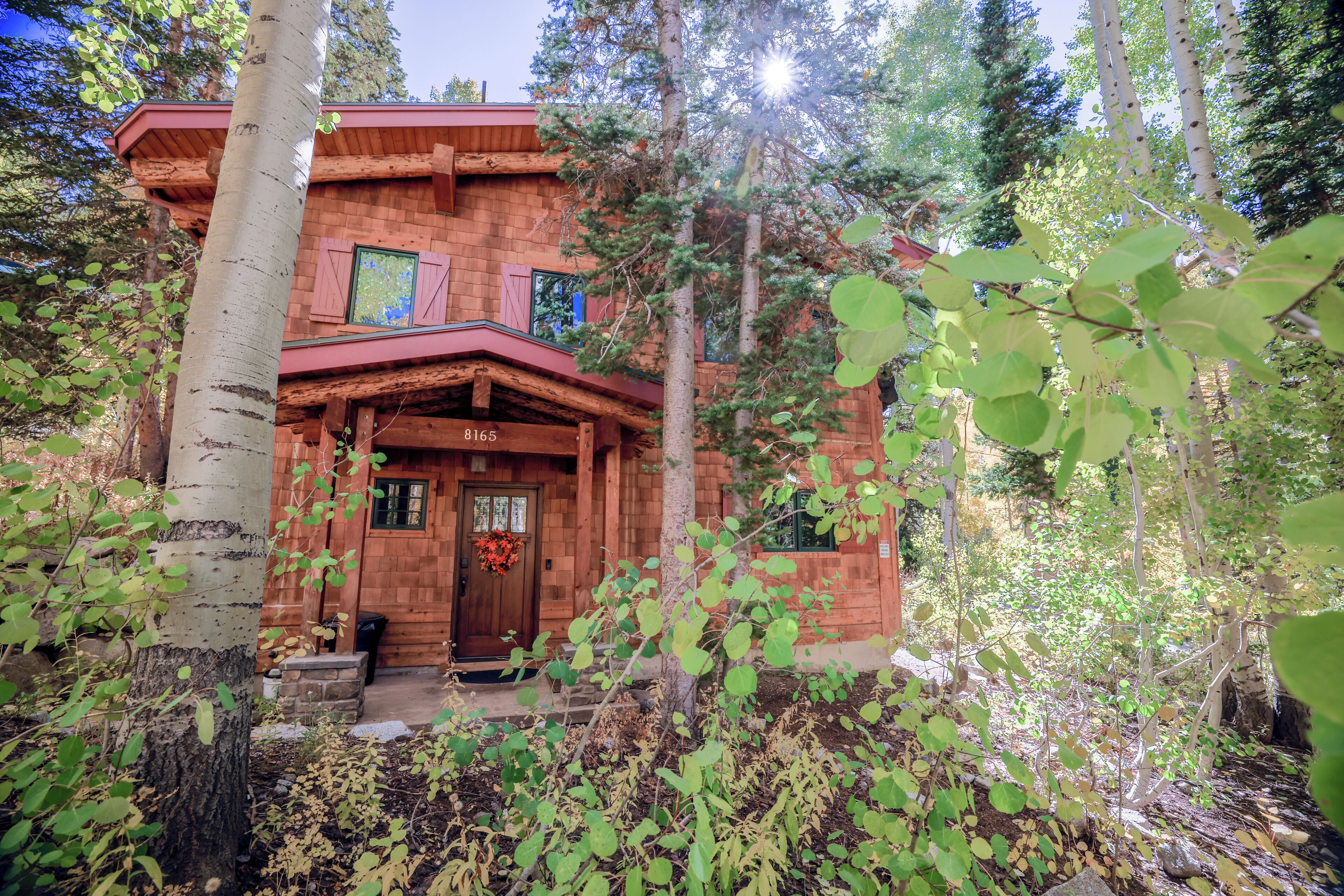 A rustic log cabin with a wooden front door, a porch, and a chimney.