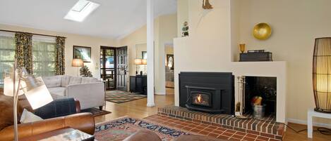 Un salón amplio con chimenea, sofás de cuero y un tapete grande.