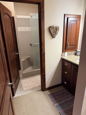 A bathroom with a shower, a wooden door, a towel rack, and a sink with a countertop. - Lux Condo in Aspens-3 min. walk to PC Mtn. Resort - 15% off '27 ski dates! (Park City)