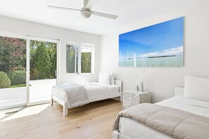 A modern bedroom with a bed, a nightstand, and a ceiling fan. - Contemporary East Hampton Retreat, Tennis + Pool (East Hampton)