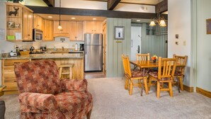 A kitchen with wooden cabinets, a stainless steel refrigerator, and a dining area with a wooden table and chairs. - Pool, Hot Tub, Weber Gas BBQ, Renovated. Easy access into unit (Steamboat Springs)