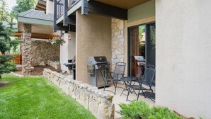 A patio with a grill, outdoor seating, and a stone wall. - Pool, Hot Tub, Weber Gas BBQ, Renovated. Easy access into unit (Steamboat Springs)
