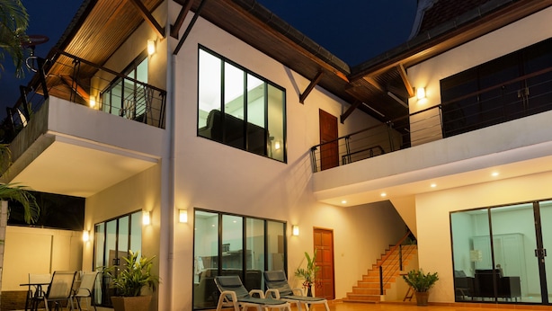 A modern two-story house with a swimming pool, outdoor seating, and a staircase leading to the upper floor.