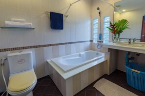 Une salle de bain équipée de toilettes, d’une baignoire, d’un lavabo et d’un panier bleu.