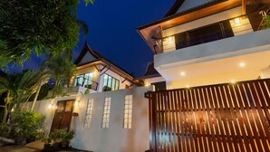 A modern house with a gated entrance, large windows, and a balcony.