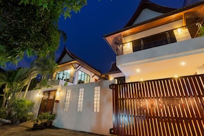 Uma casa moderna com portão fechado, grandes janelas e varanda.