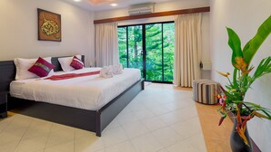 A modern hotel bedroom with a large bed, a view of greenery through the window, and a decorative plant.