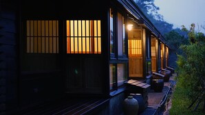 Ein traditionelles japanisches Gebäude mit Schiebetüren und einem kleinen Sitzbereich im Freien mit Bänken und einer großen Vase.