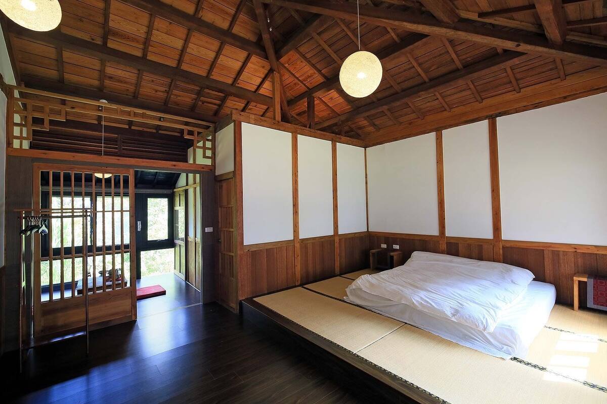 Une pièce de style japonais traditionnel, avec un sol recouvert de tatamis, un lit bas et des portes coulissantes.
