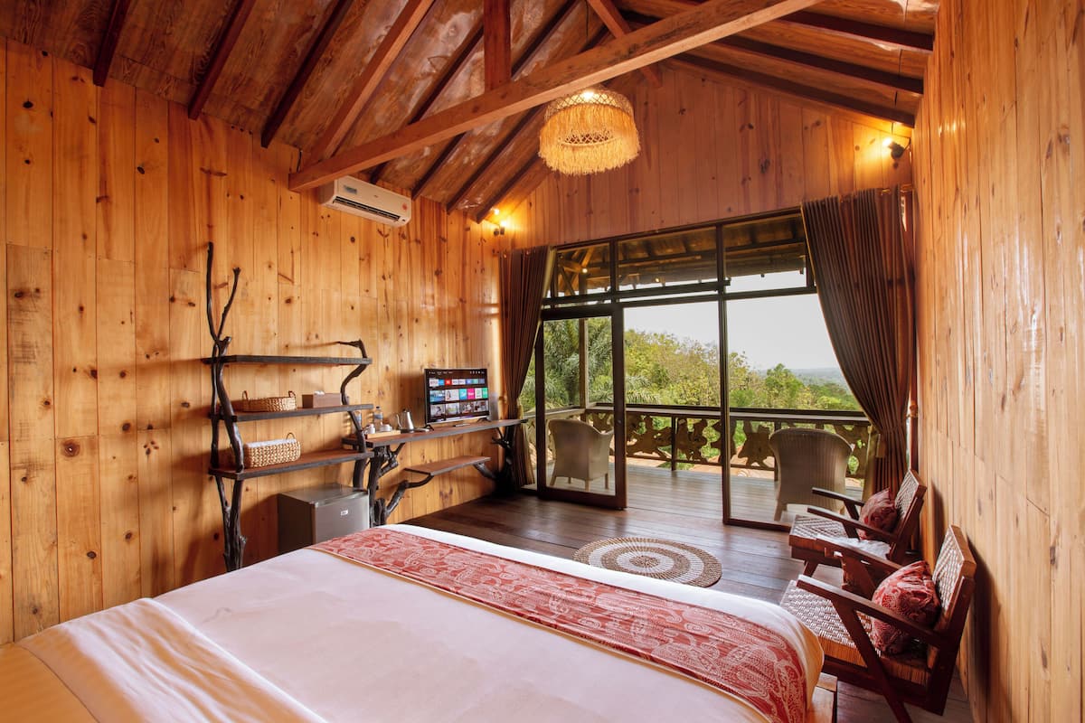 A wooden cabin bedroom with a bed, a desk, and a chair.