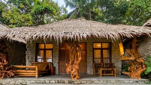 A rustic hut with a thatched roof, stone walls, and a wooden door. - RAJAKLANA Resort, Villa And Spa (Bangunjiwo)