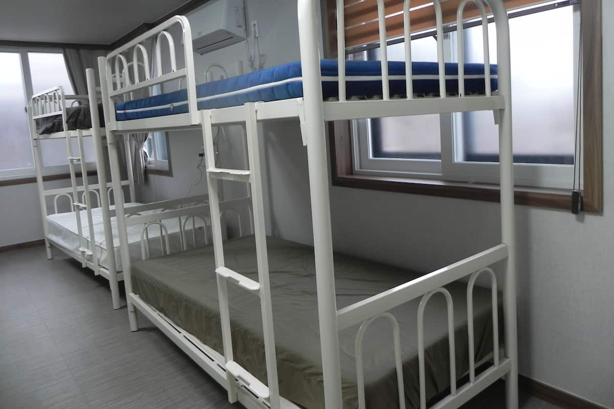 A bunk bed room with a window and a radiator.