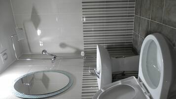 A bathroom with a shower, toilet, and a round mirror with a glittery frame.