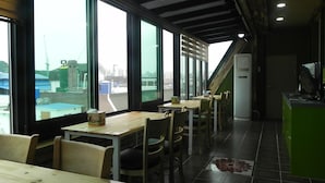A restaurant with large windows, wooden tables, and chairs.