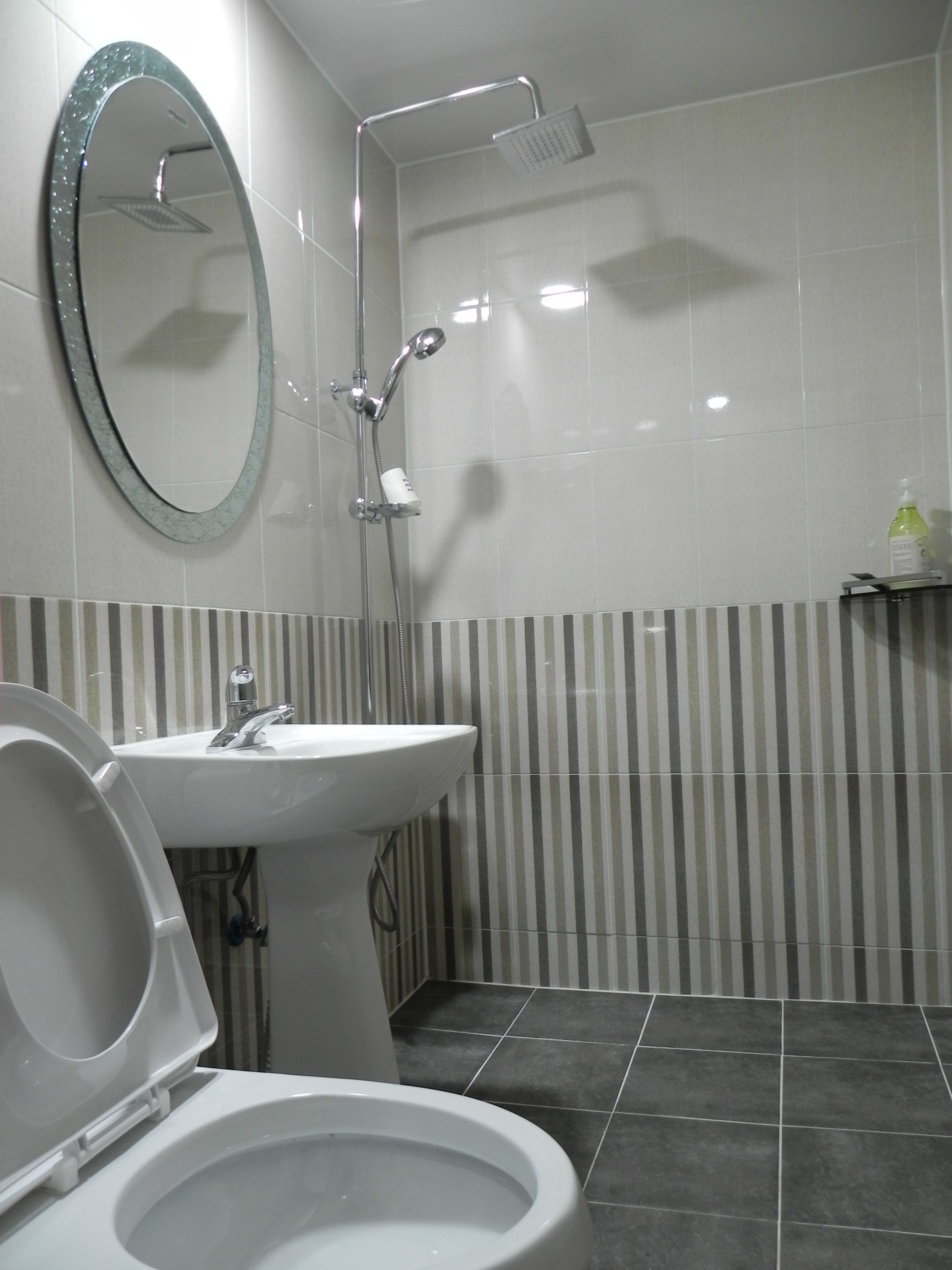 Moderni kylpyhuone, jossa on wc, pesuallas ja suihku.