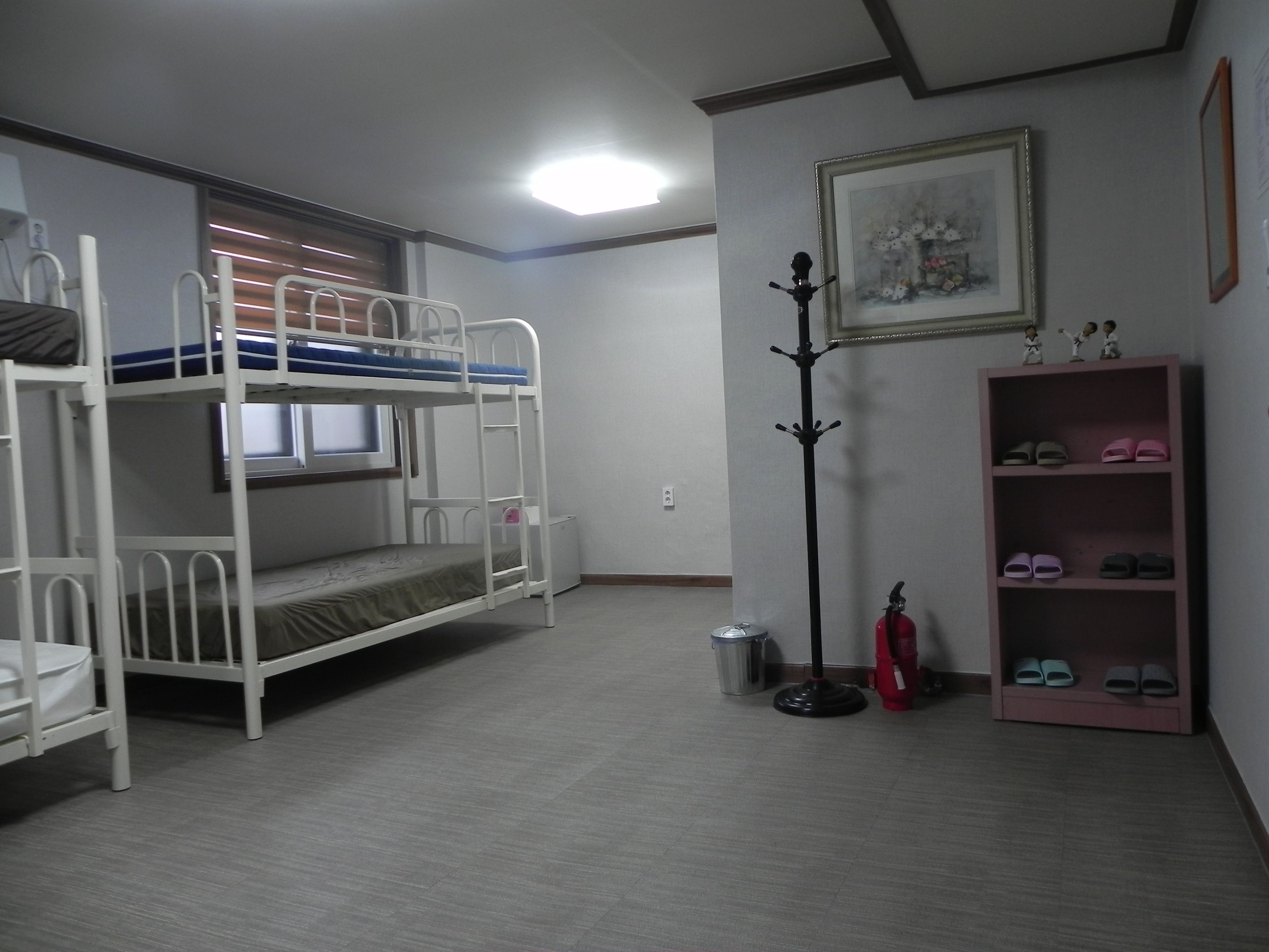Habitación con literas, un perchero, un cuadro enmarcado y un estante para zapatos.