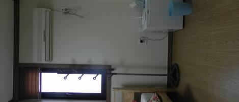 A room with a window, an air conditioner, a small table with a tissue box, and a patterned sofa.