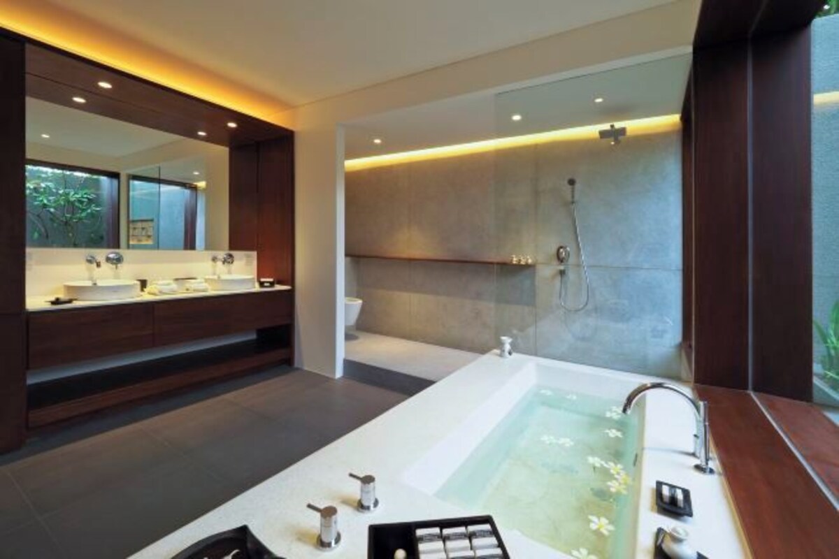 A modern bathroom with a large bathtub, a vanity with a mirror, and a shower area.