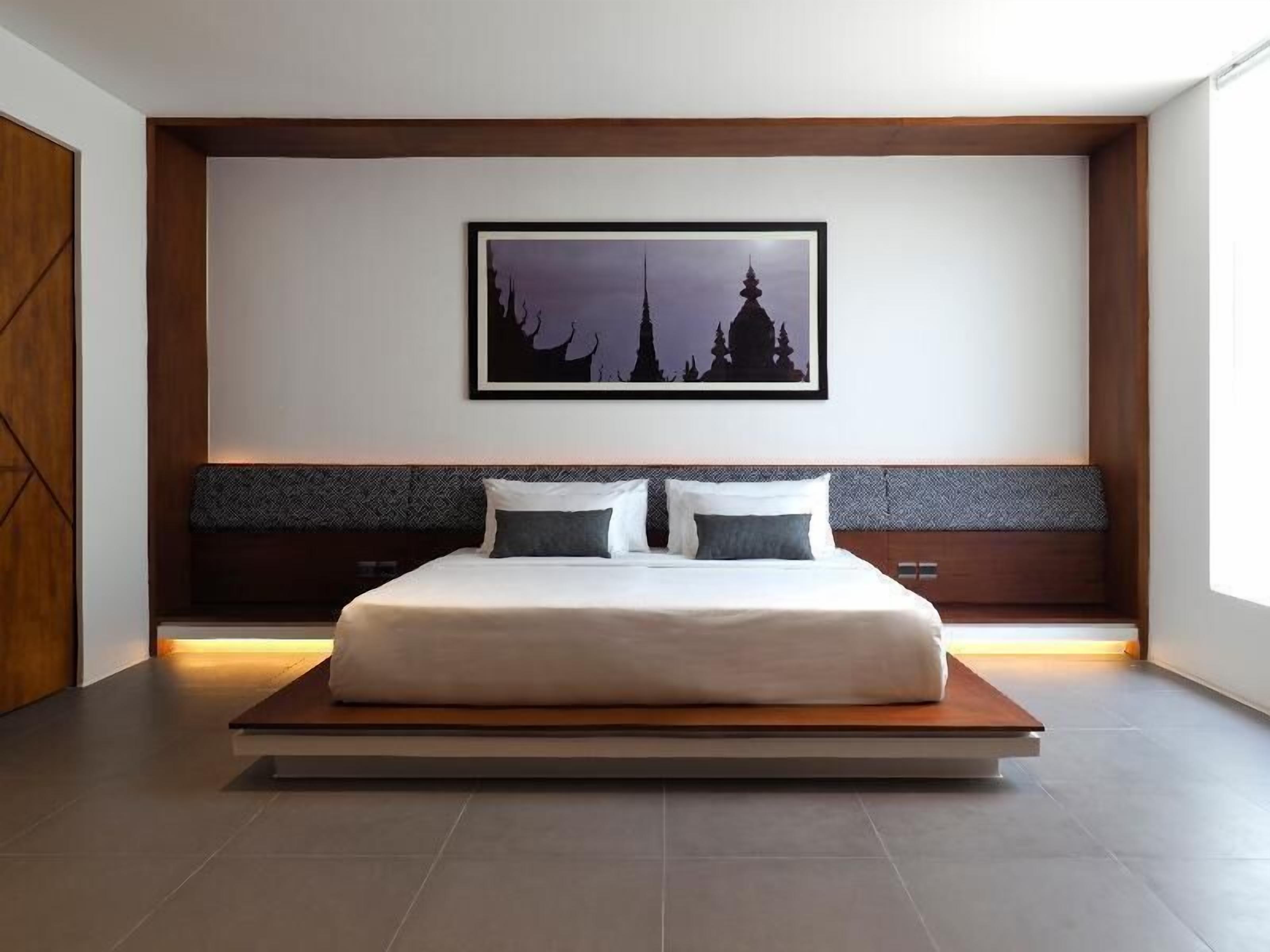 A modern bedroom with a large bed, a framed picture on the wall, and a wooden headboard.
