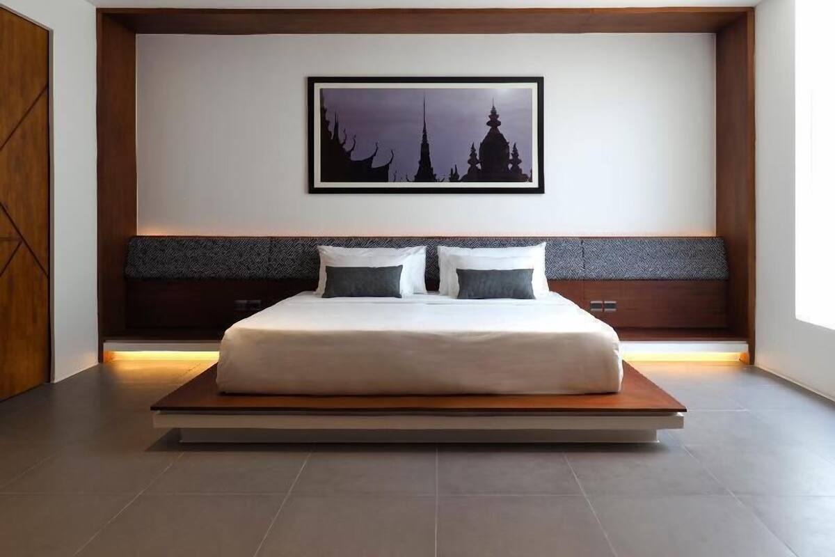 A modern bedroom with a large bed, a framed picture on the wall, and a wooden headboard.
