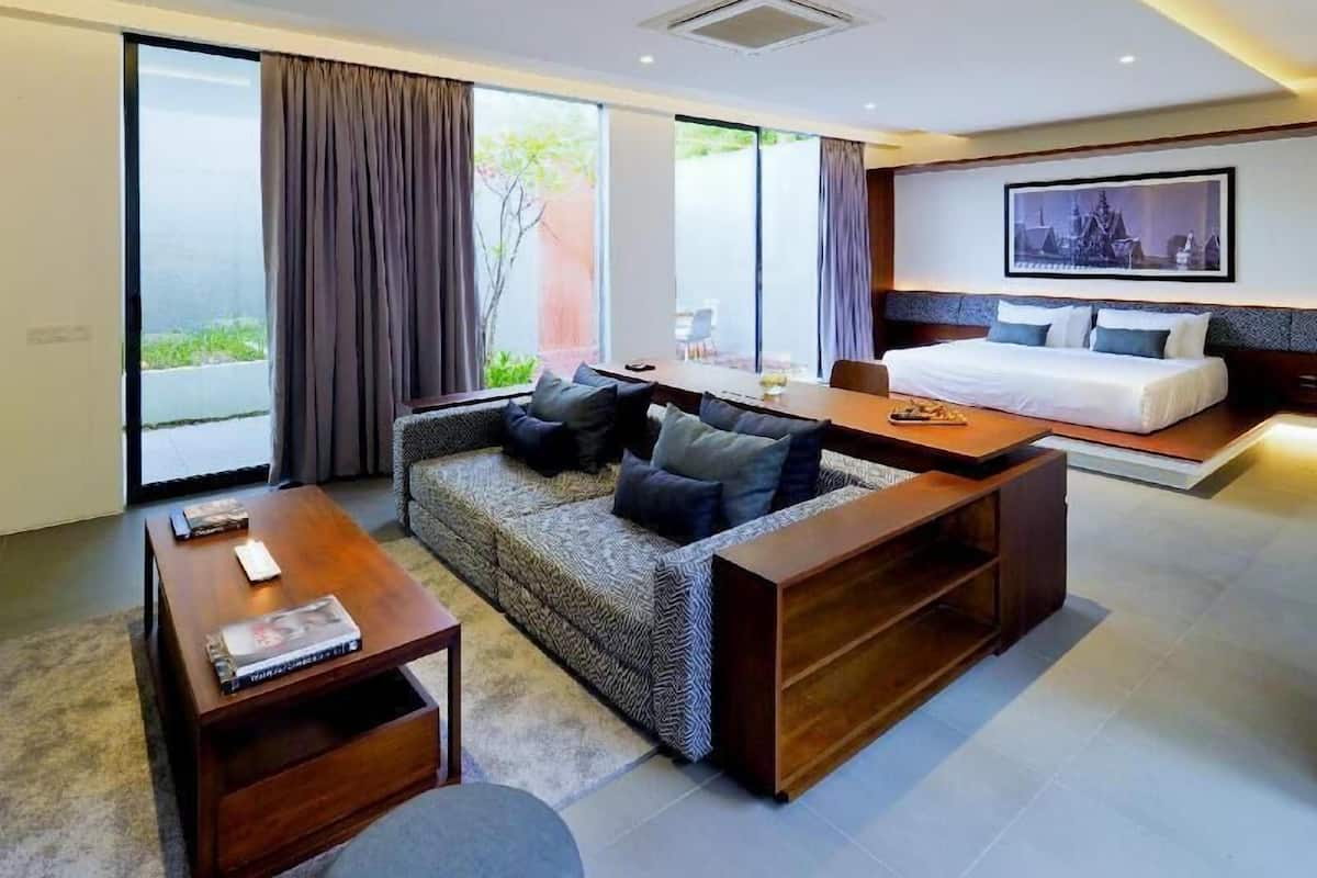 A modern hotel room with a sofa, a dining table, a bed, and large windows.