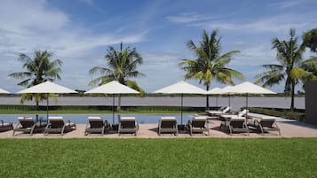 Una piscina al aire libre, sombrillas, sillones reclinables de piscina