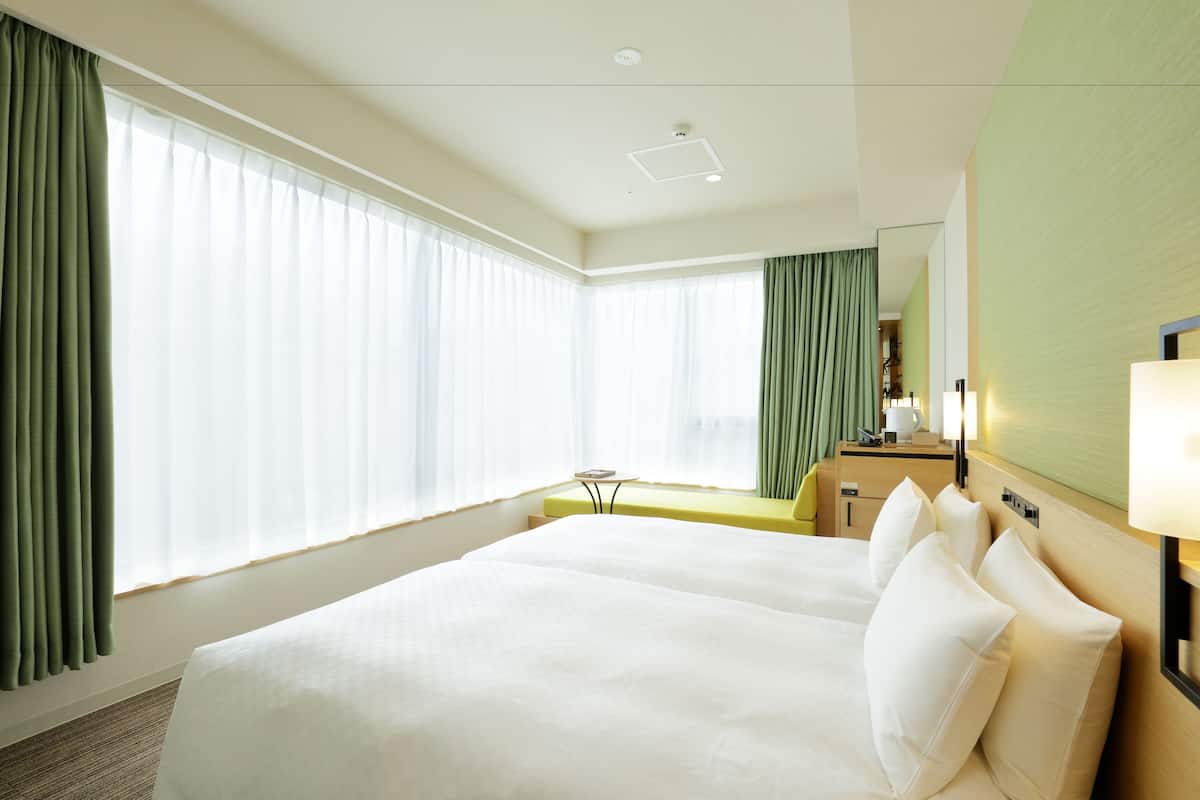 A hotel room with a large bed, a desk, and a mirror.