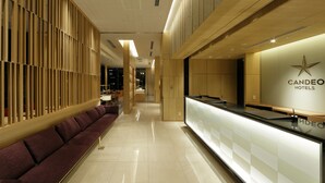 A modern hotel lobby with a reception desk, seating area, and a wooden partition. - Candeo Hotels Tokyo Shimbashi (Tokyo)