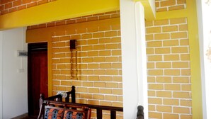 A room with a brick wall, wooden bench, and a door. - Shyni Tourist Guesthouse (Hikkaduwa)