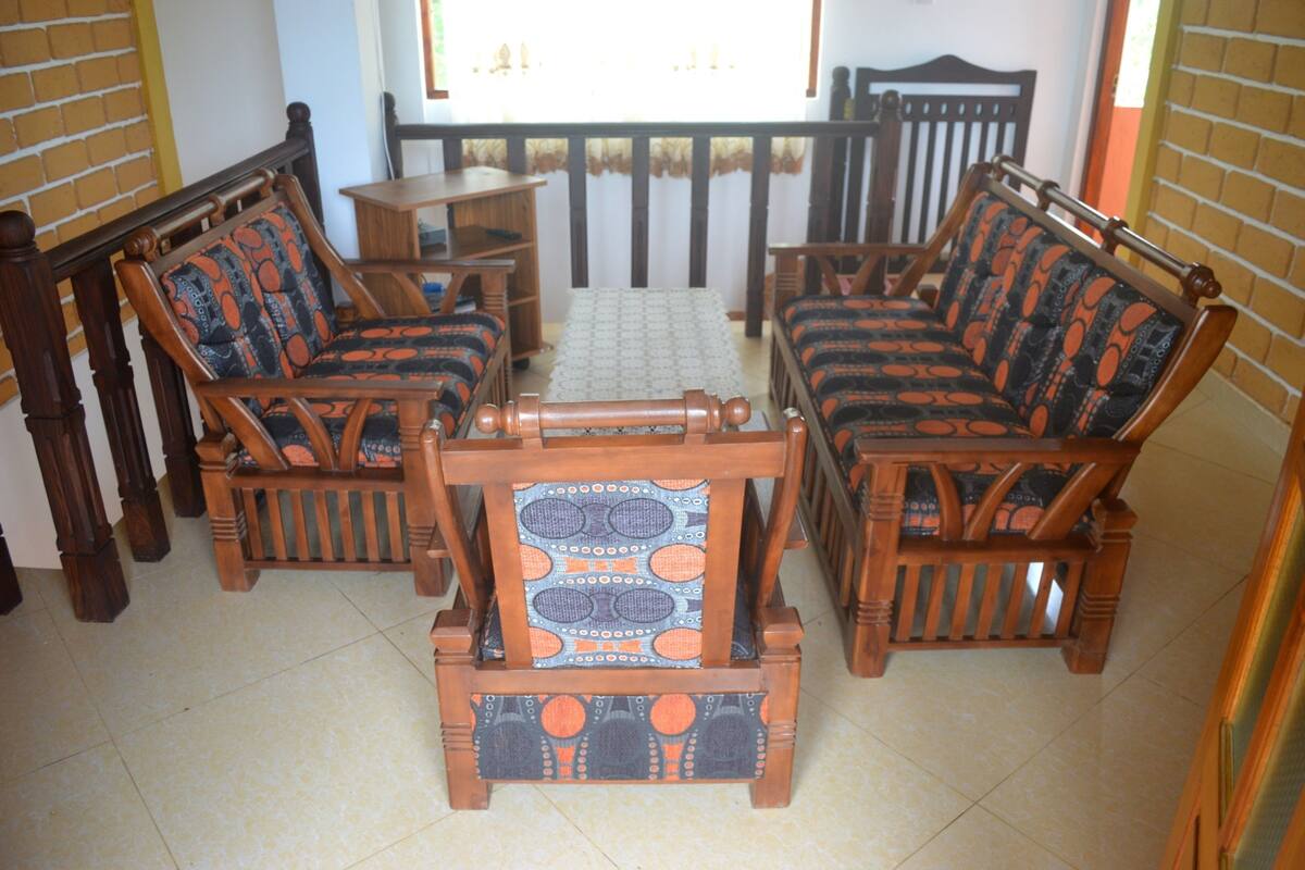 Une pièce comprenant un ensemble de canapés en bois, une table basse en bois et un tapis à motifs.